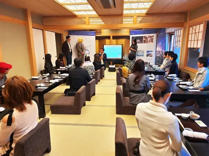 Attendees seated in a traditional Japanese room listening to a presentation about integrated living developments.