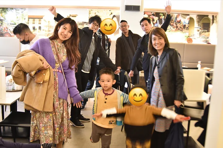 旅行をテーマにした壁画のあるレストランで、大人と子供たちが楽しそうにポーズをとっている。