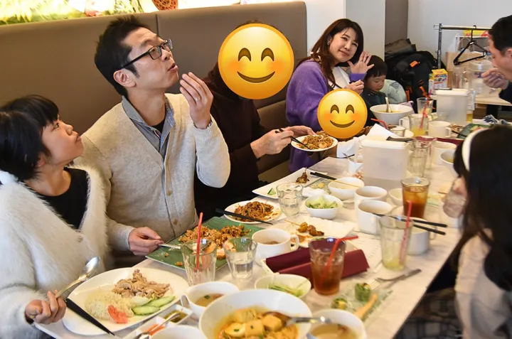 食事が並んだテーブルを囲んで食事を楽しむ人々のグループ。