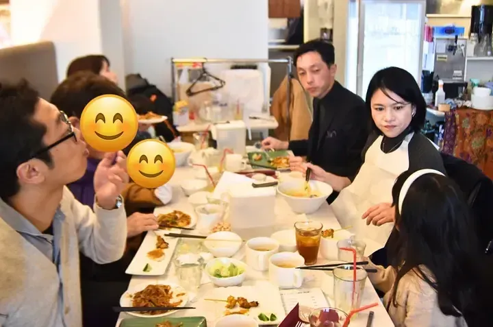 Friends enjoying a meal together at a restaurant table filled with various dishes and drinks.
