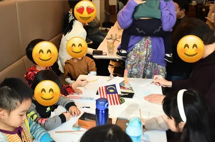Children drawing Malaysian flags at a table during a cultural activity session.