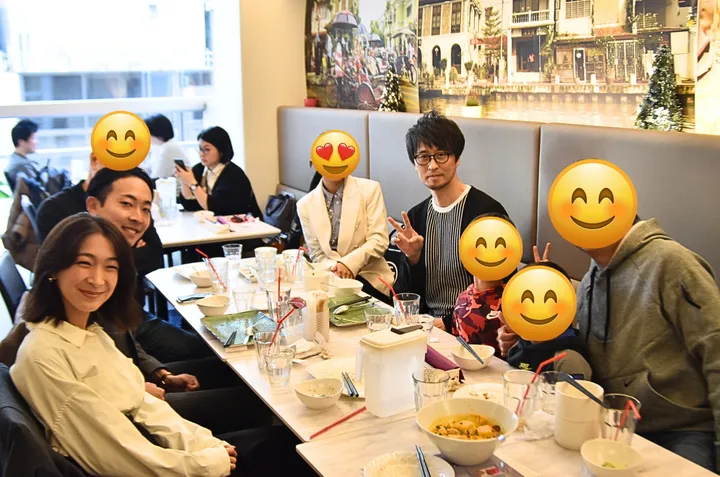 運河の壁画が描かれたレストランで食事をする友人たちのグループ。テーブルにはスープや飲み物が並んでいる。