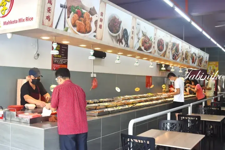 Customers ordering from a buffet-style food counter at Mahkota Mix Rice, with menu displays above the serving area.