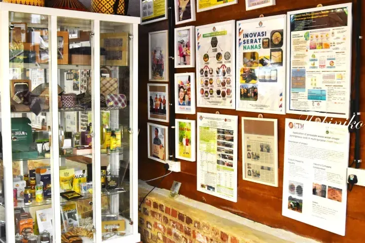 Display cabinet with pineapple products and wall posters showcasing pineapple fiber innovation and research at a Malaysian venue.