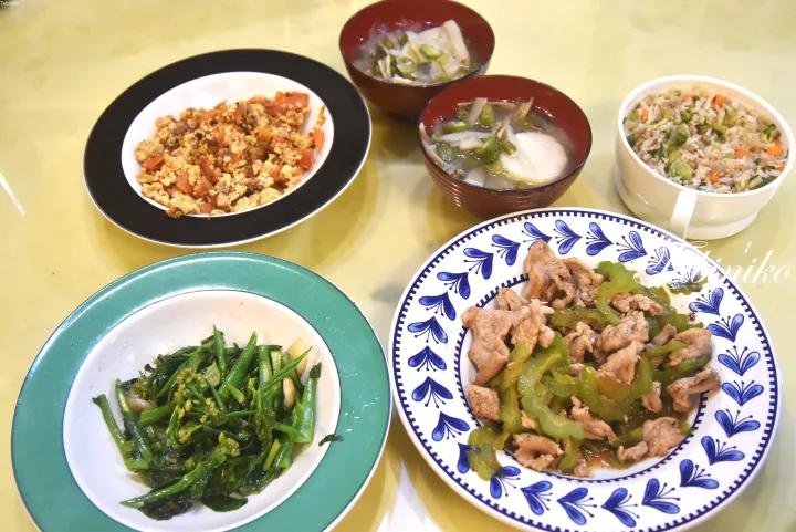 トマト卵炒め、ゴーヤチャンプルー、炒め野菜、チャーハン、スープが並んだテーブル。