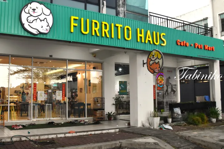 緑色の看板と犬と猫のロゴが特徴的なFURRITO HAUS Cafe・Pet Martの外観。ガラス窓からは店内の席が見える。