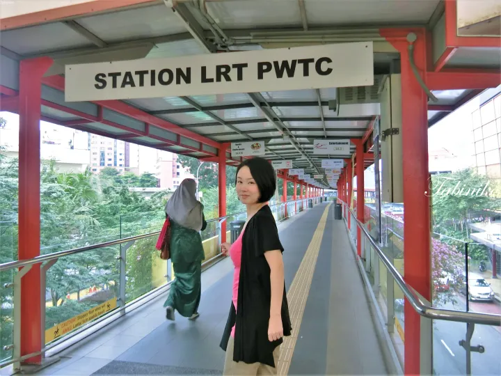 マレーシアのSTATION LRT PWTCの看板の下に立つ女性。