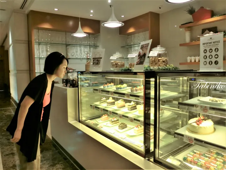 Sunwayホテルのカフェで、ガラスケース内のデザートを選ぶ女性。