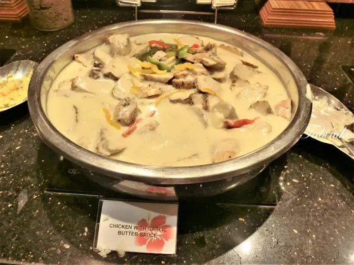 Chicken with garlic butter sauce served in a buffet chafing dish with a label.