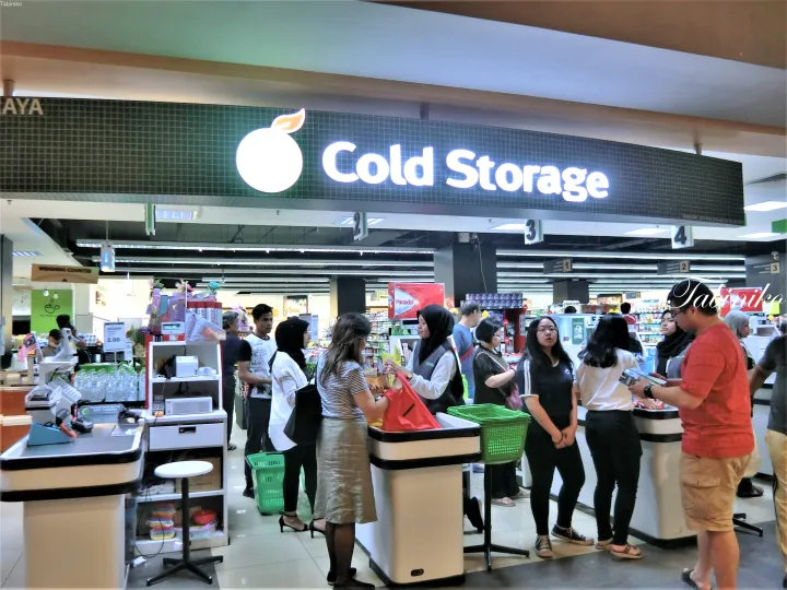マレーシアのスーパーマーケットで、Cold Storageの看板の下でレジに並ぶ客たち。