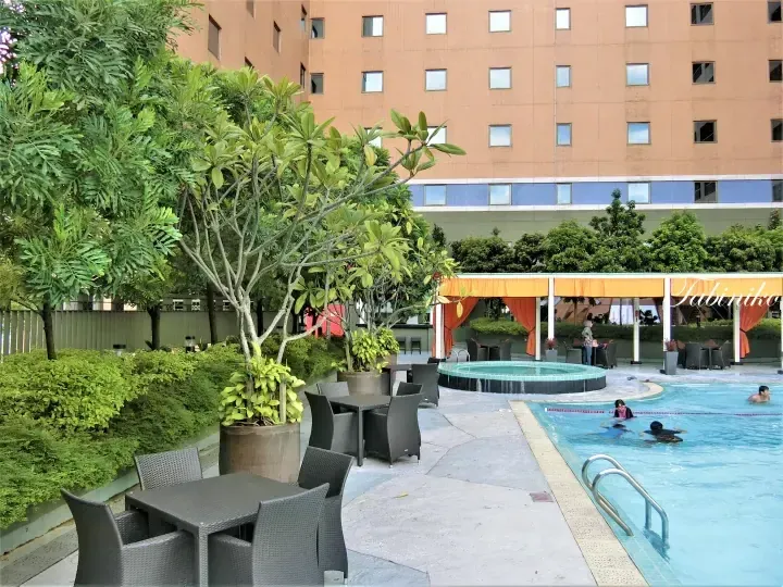 Outdoor swimming pool with lounge chairs and greenery at a hotel in Malaysia