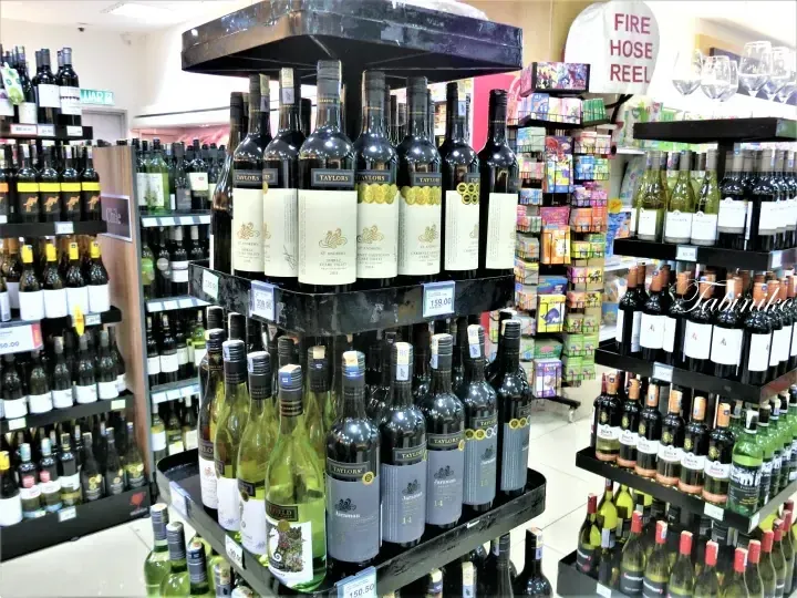 Taylors wine bottles displayed on a rotating rack in a well-stocked liquor store aisle.