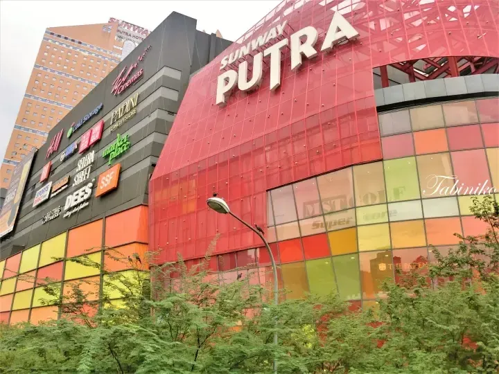 Sunway Putra shopping mall exterior with red facade and store signs including H&M and Uniqlo.