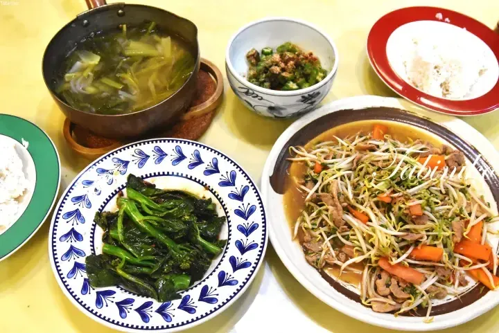 Traditional Malaysian meal featuring stir-fried bean sprouts with pork, stir-fried greens, soup, and rice.