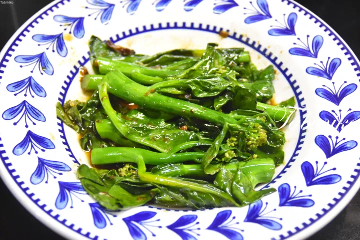 青い花柄の白い皿に盛られた炒め菜の花。